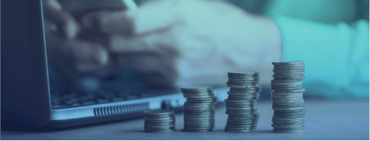 monedas frente a unas manos escribiendo en un m&oacute;vil